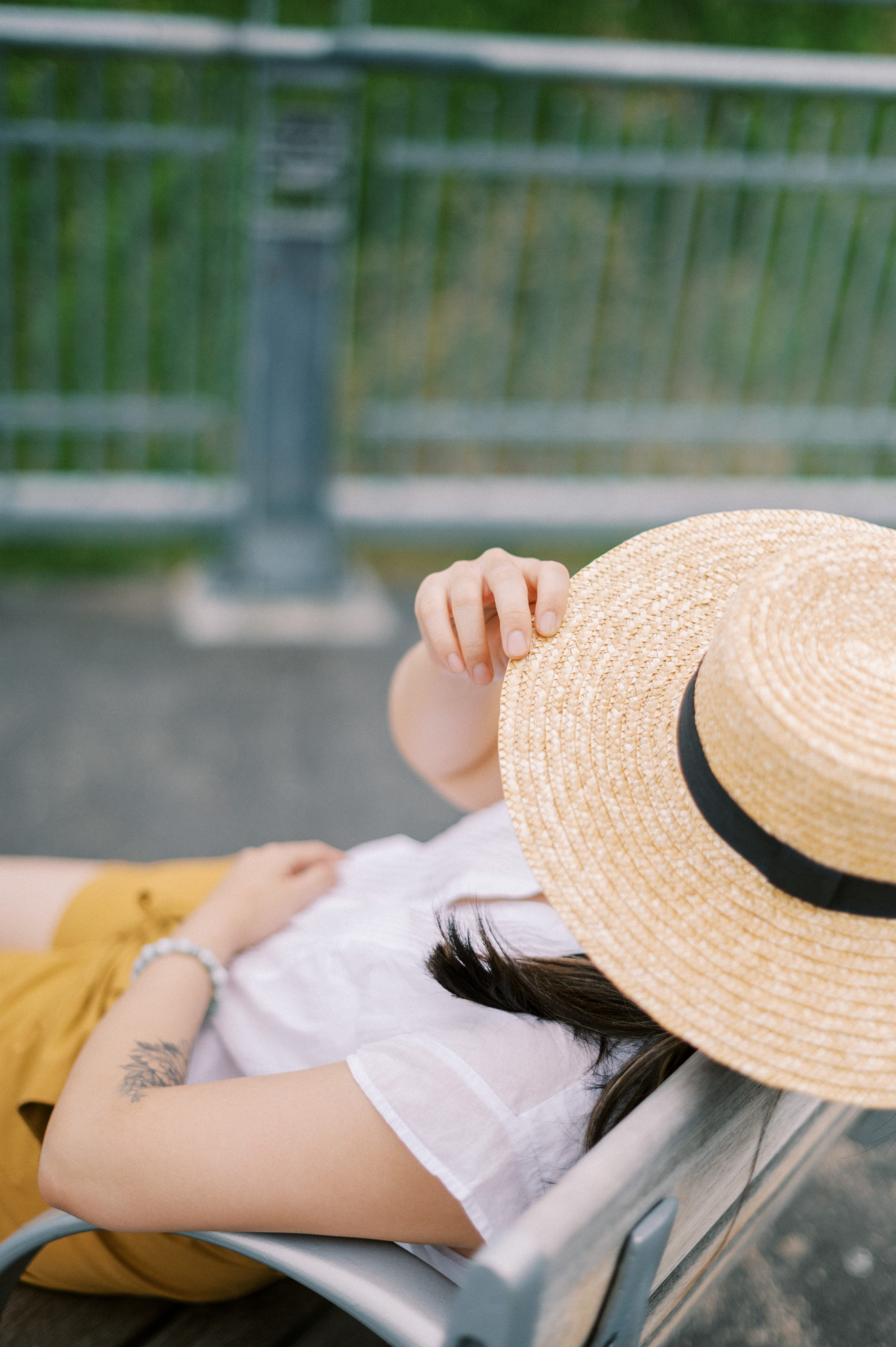 Woman resting on bench with hat pulled over head