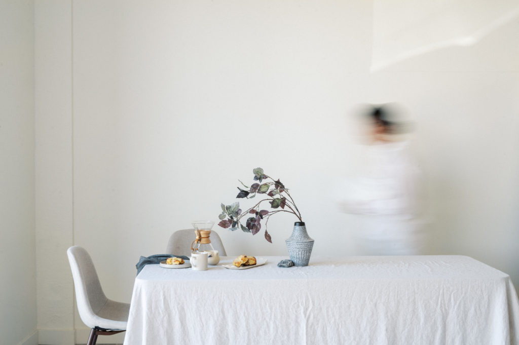 Edmonton Personal Branding Photography Blurry woman walking behind breakfast table against white wall