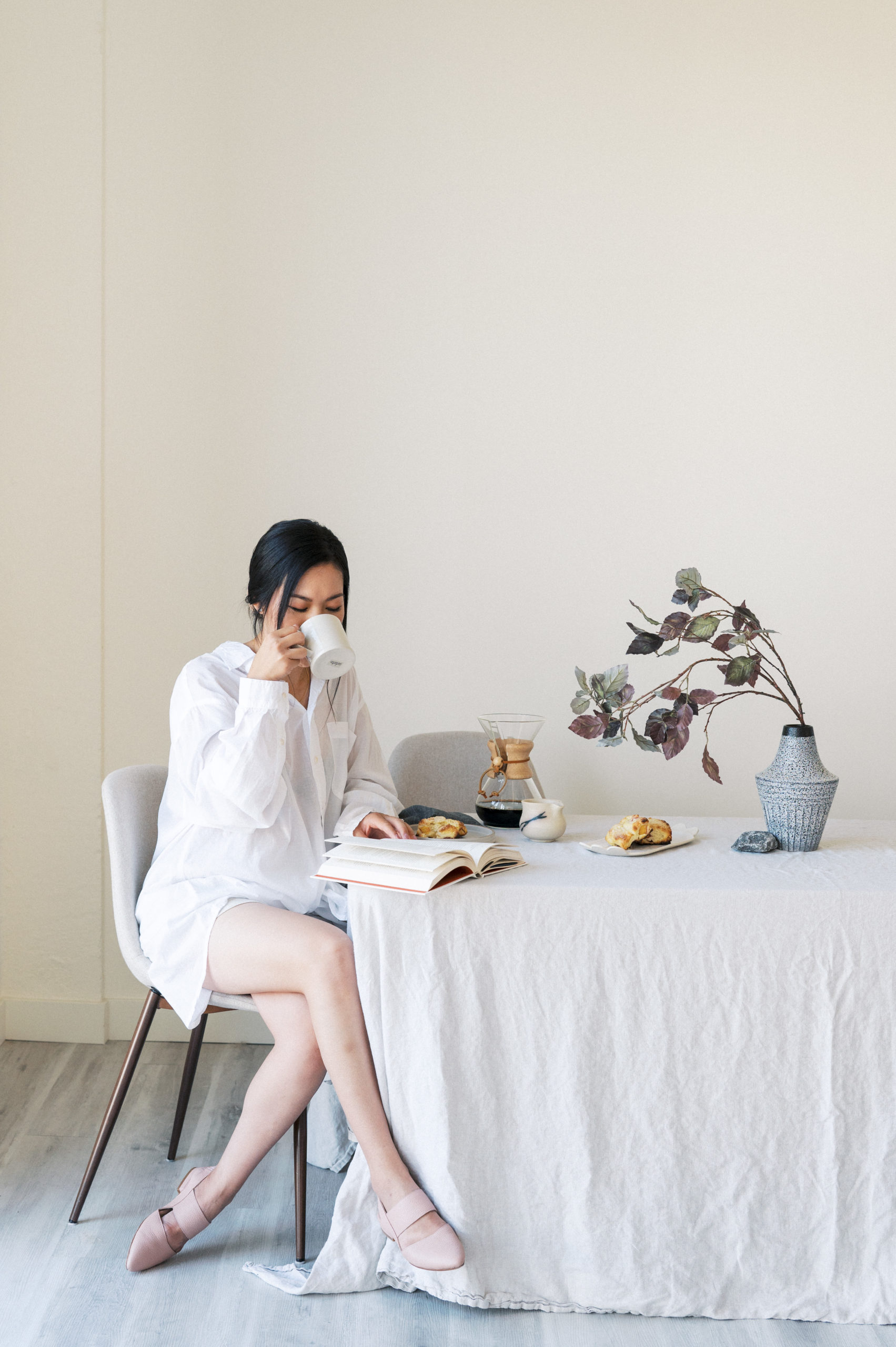 Edmonton Personal Branding Photography  Woman sitting and drinking coffee at a table with linen table cloth while reading a book